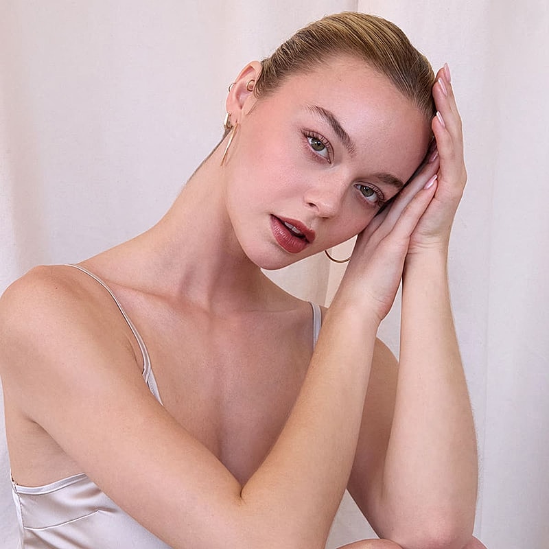 Woman posing elegantly with hands on her face.