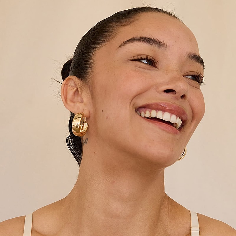 Smiling woman wearing gold hoop earrings.