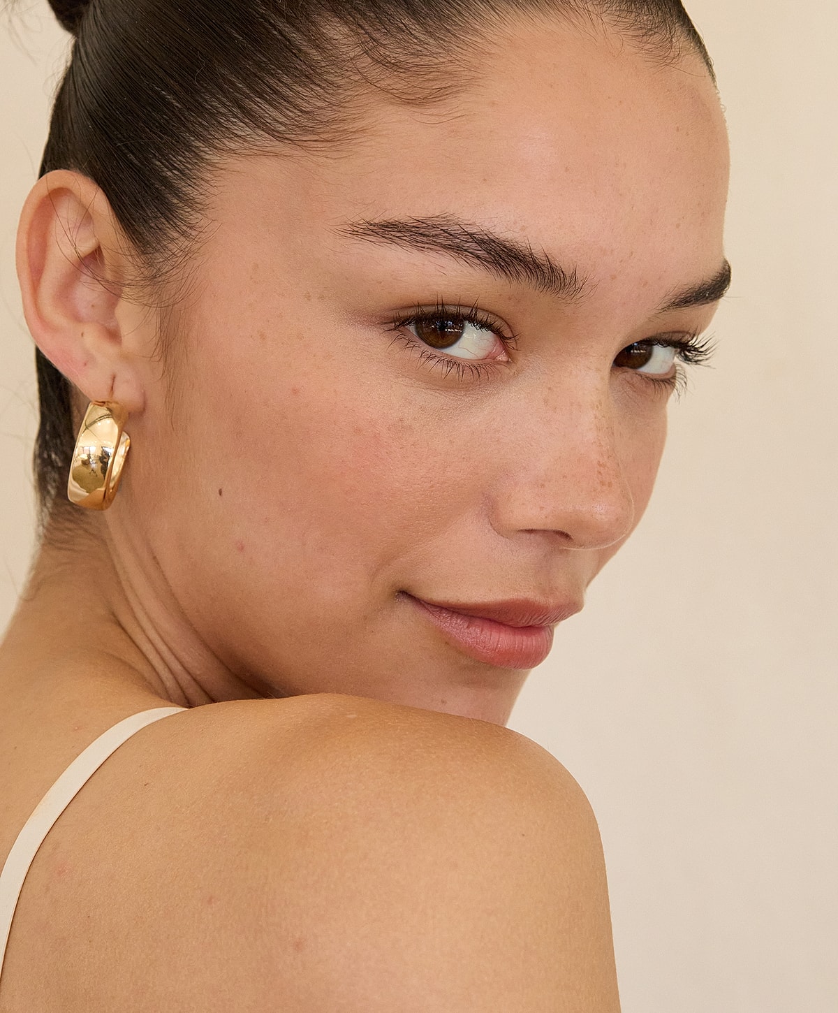 Close-up of woman with hoop earrings and natural makeup.