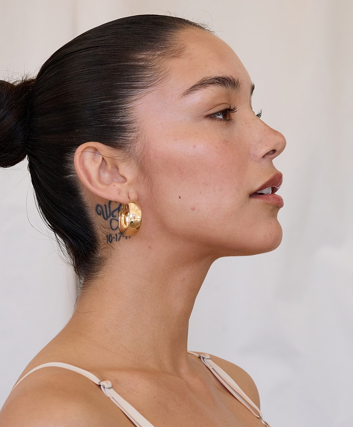 Profile of a woman with earrings and tattoo.