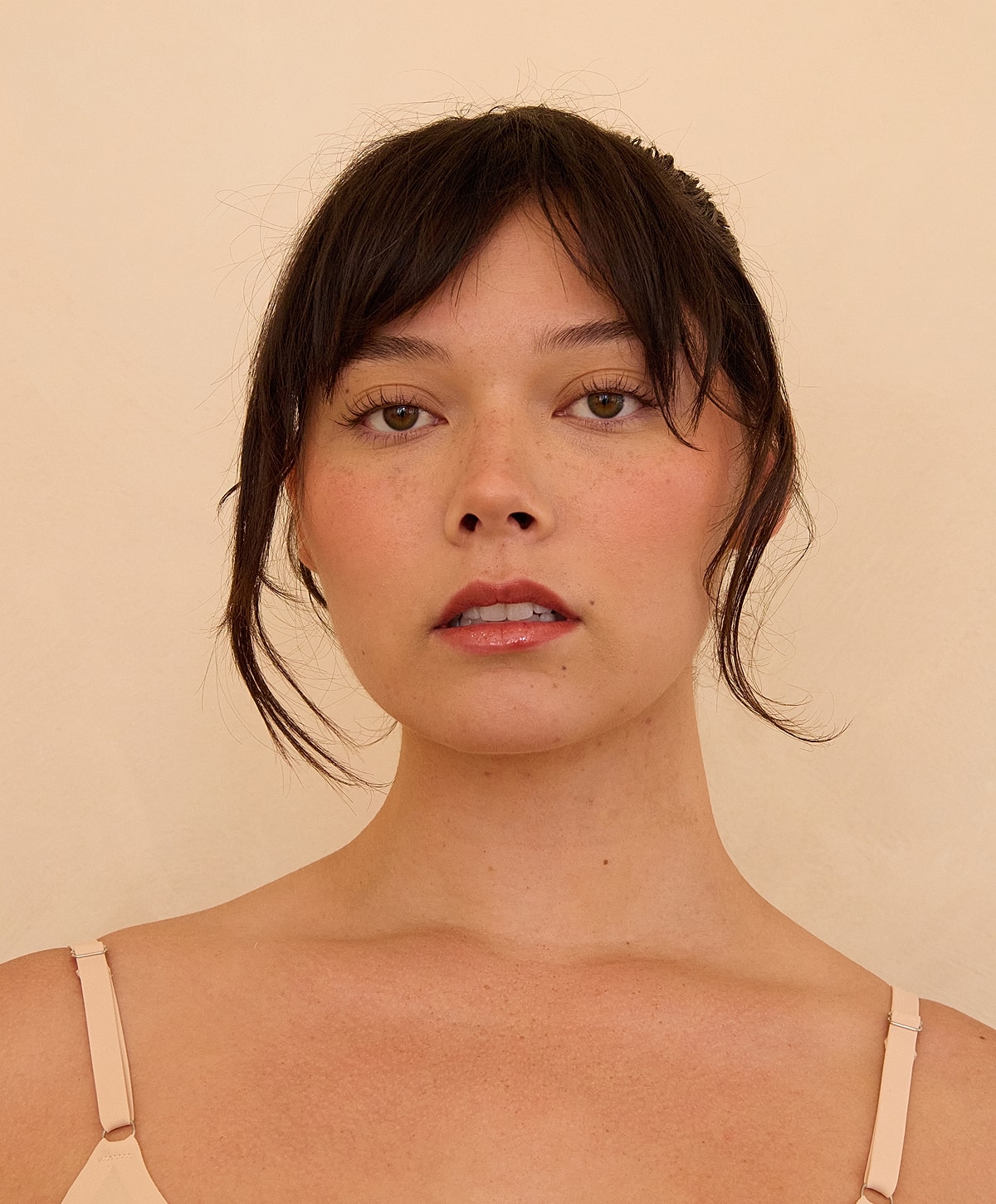 Woman with natural makeup against a neutral background.