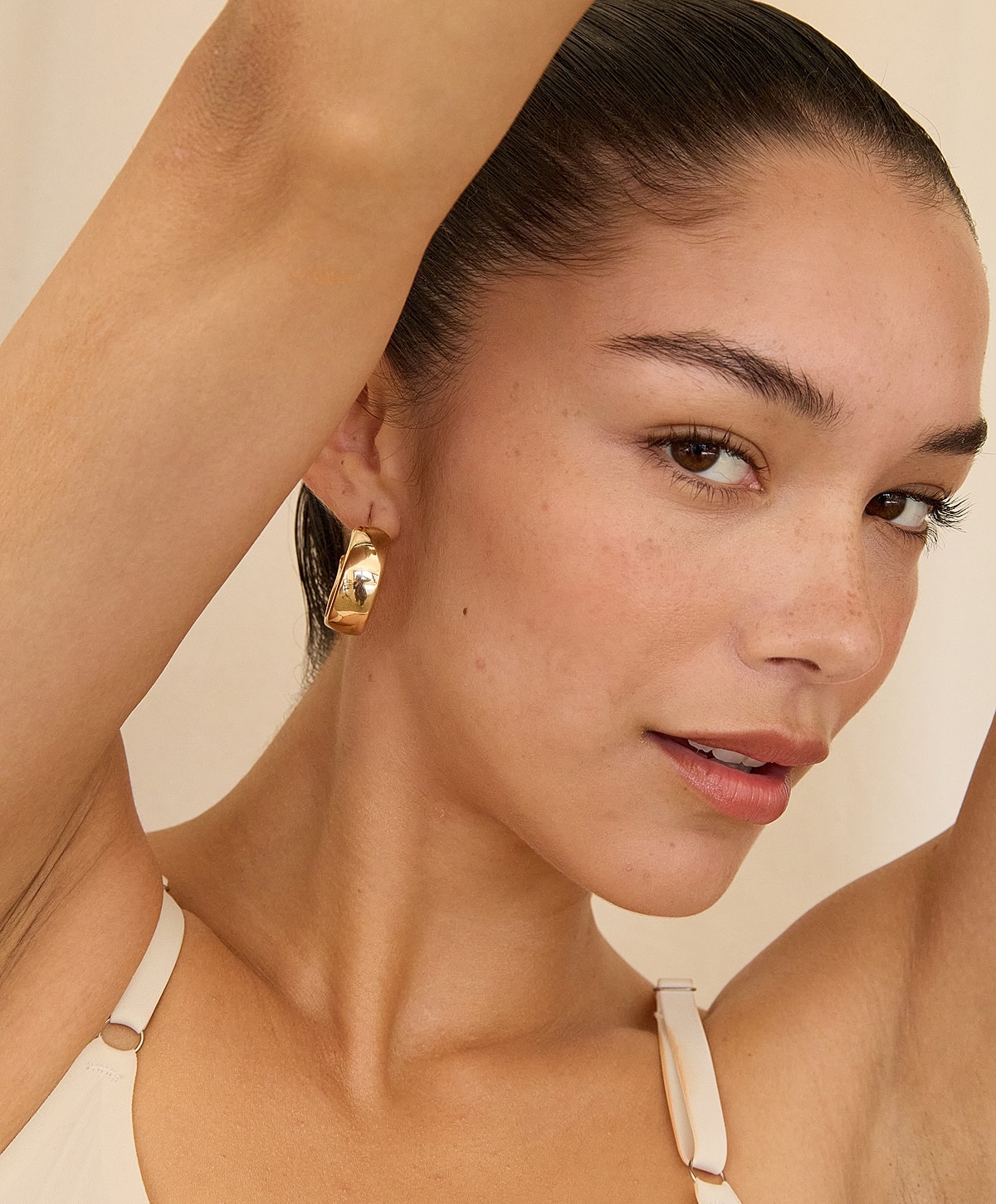 Model showcasing gold hoop earrings and hairstyle.