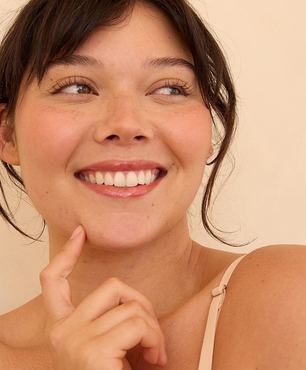 Smiling woman with finger on chin, natural beauty.