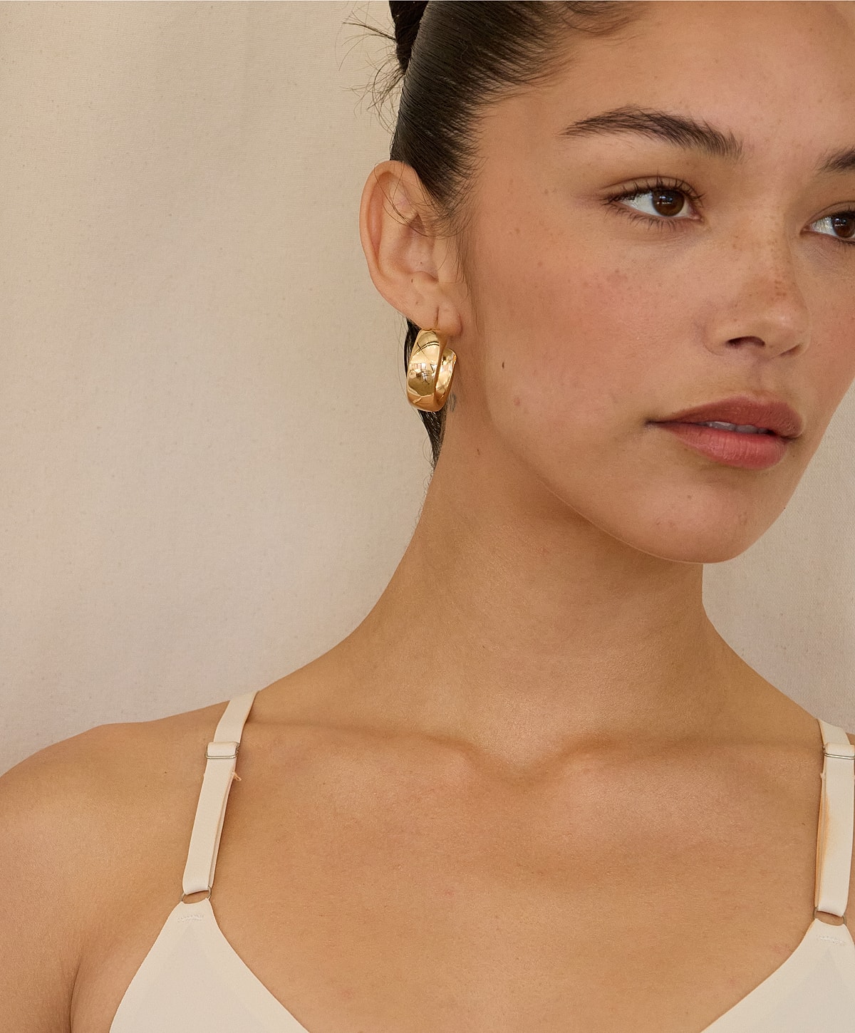 Model showcasing gold hoop earrings.