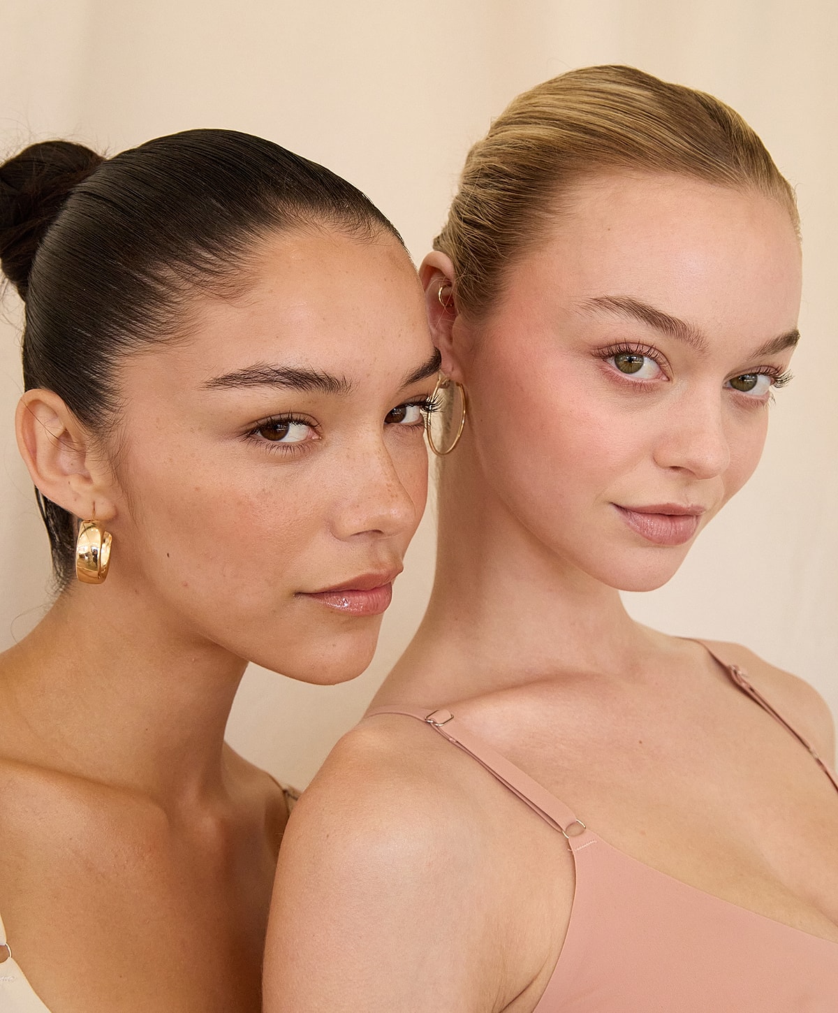 Two women posing together with earrings.