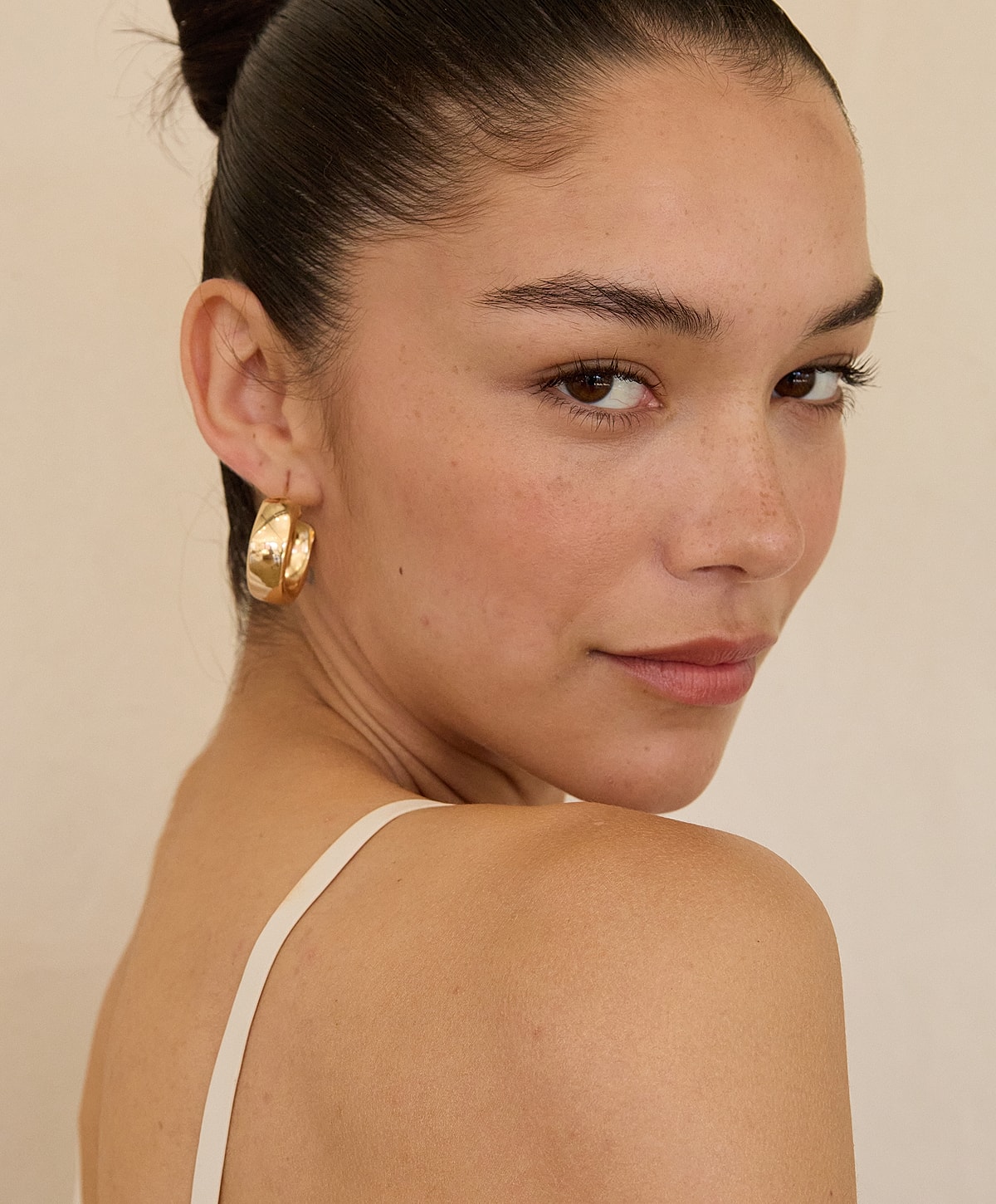 Woman with earrings and sleek hairstyle.