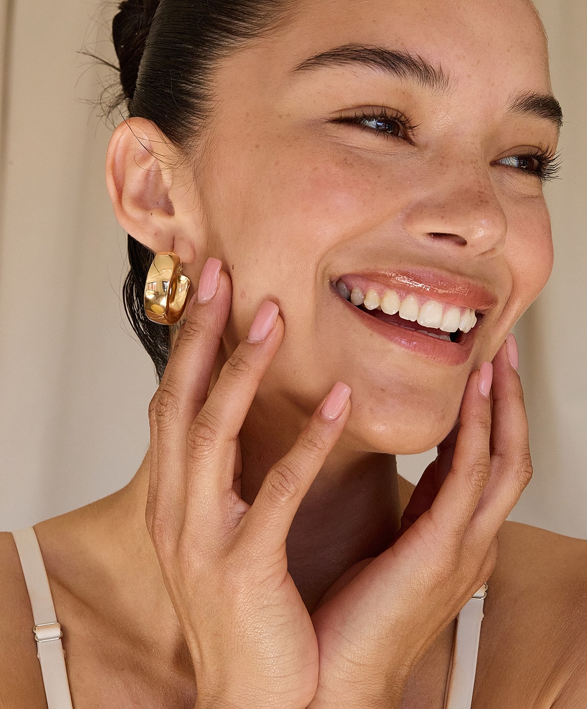 Smiling woman with gold hoop earrings.