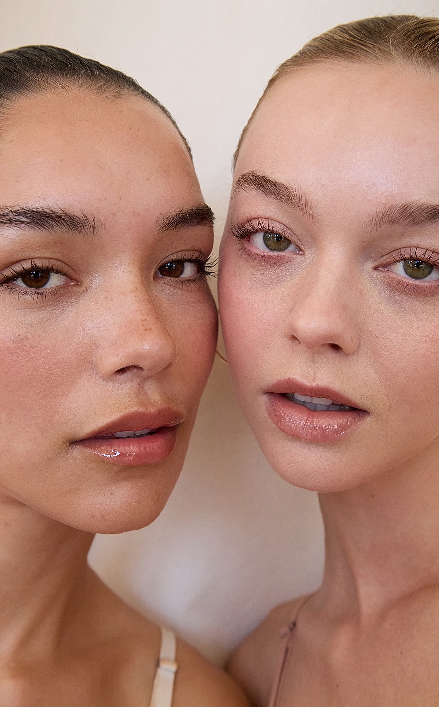 Two women posing closely together, natural makeup.