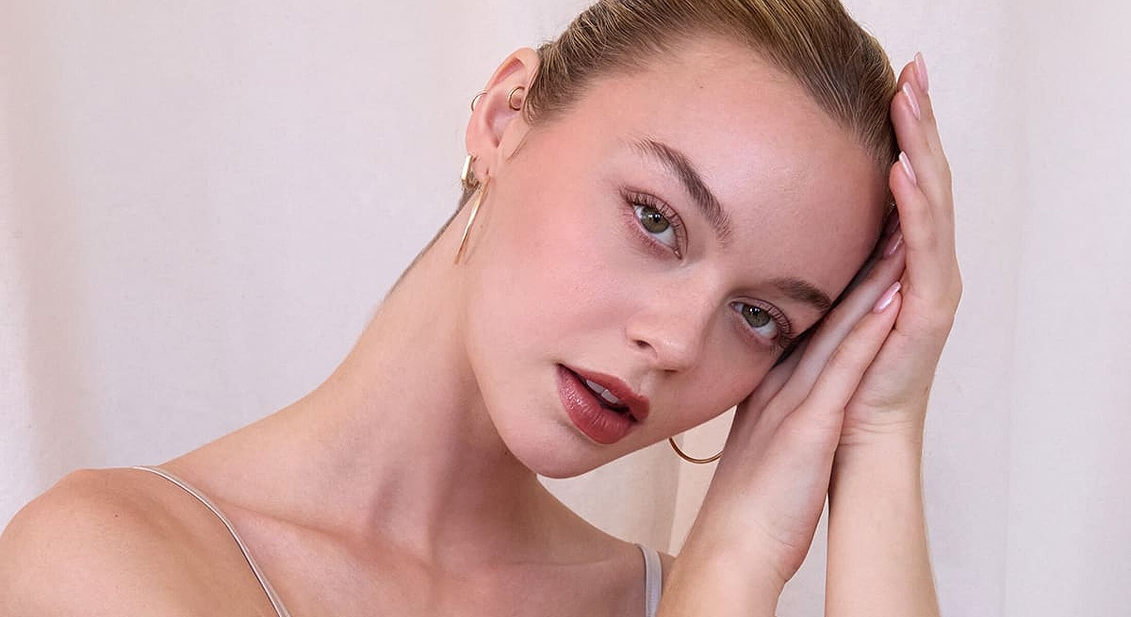 Young woman posing with thoughtful expression and earrings.