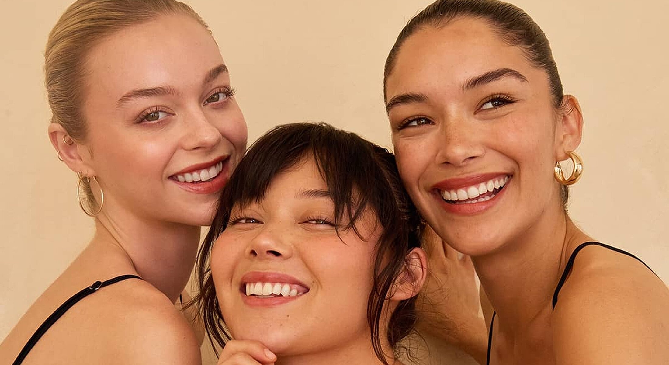 Three smiling women posing together playfully.