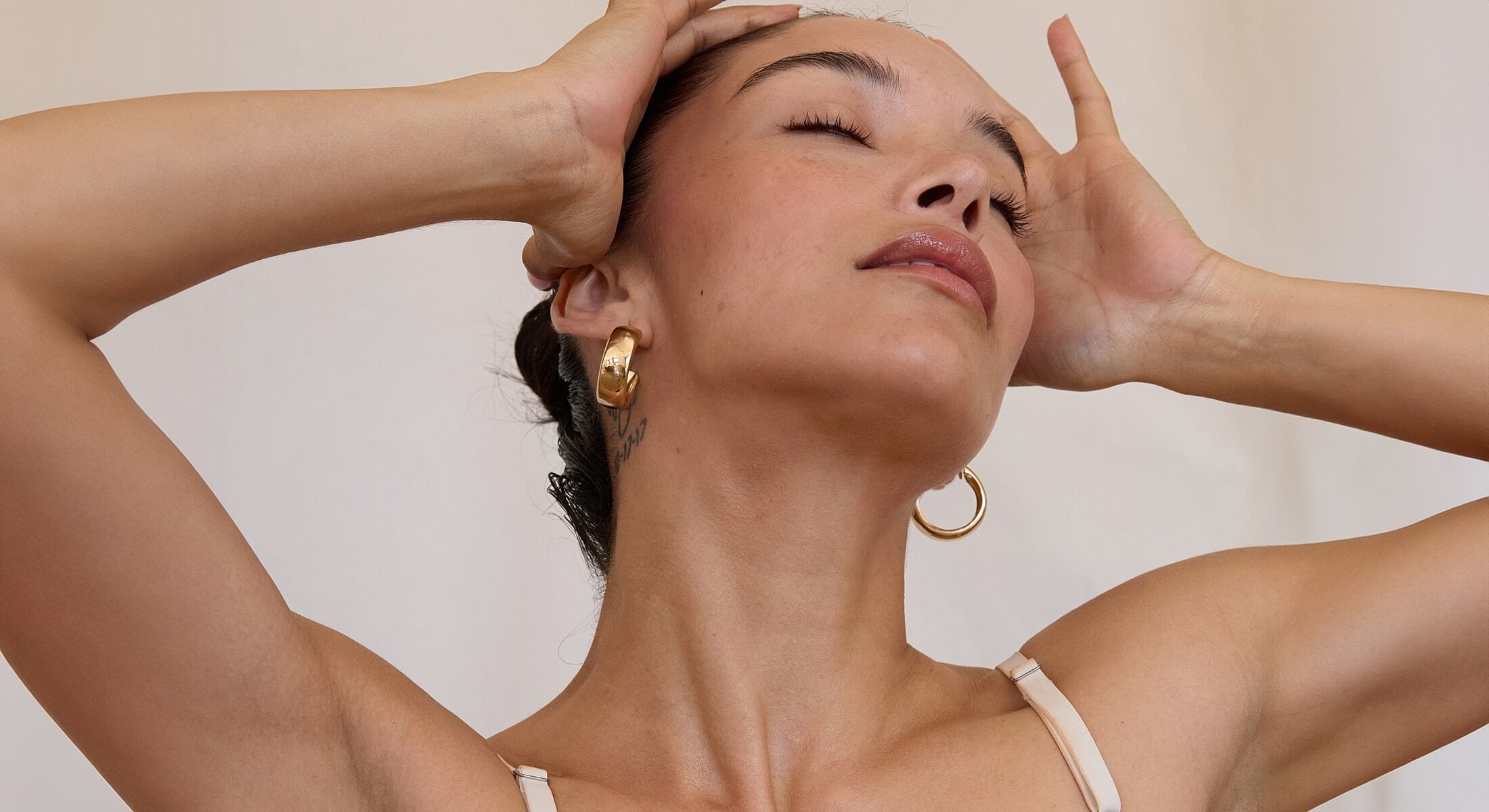 Woman with earrings posing against a neutral backdrop.