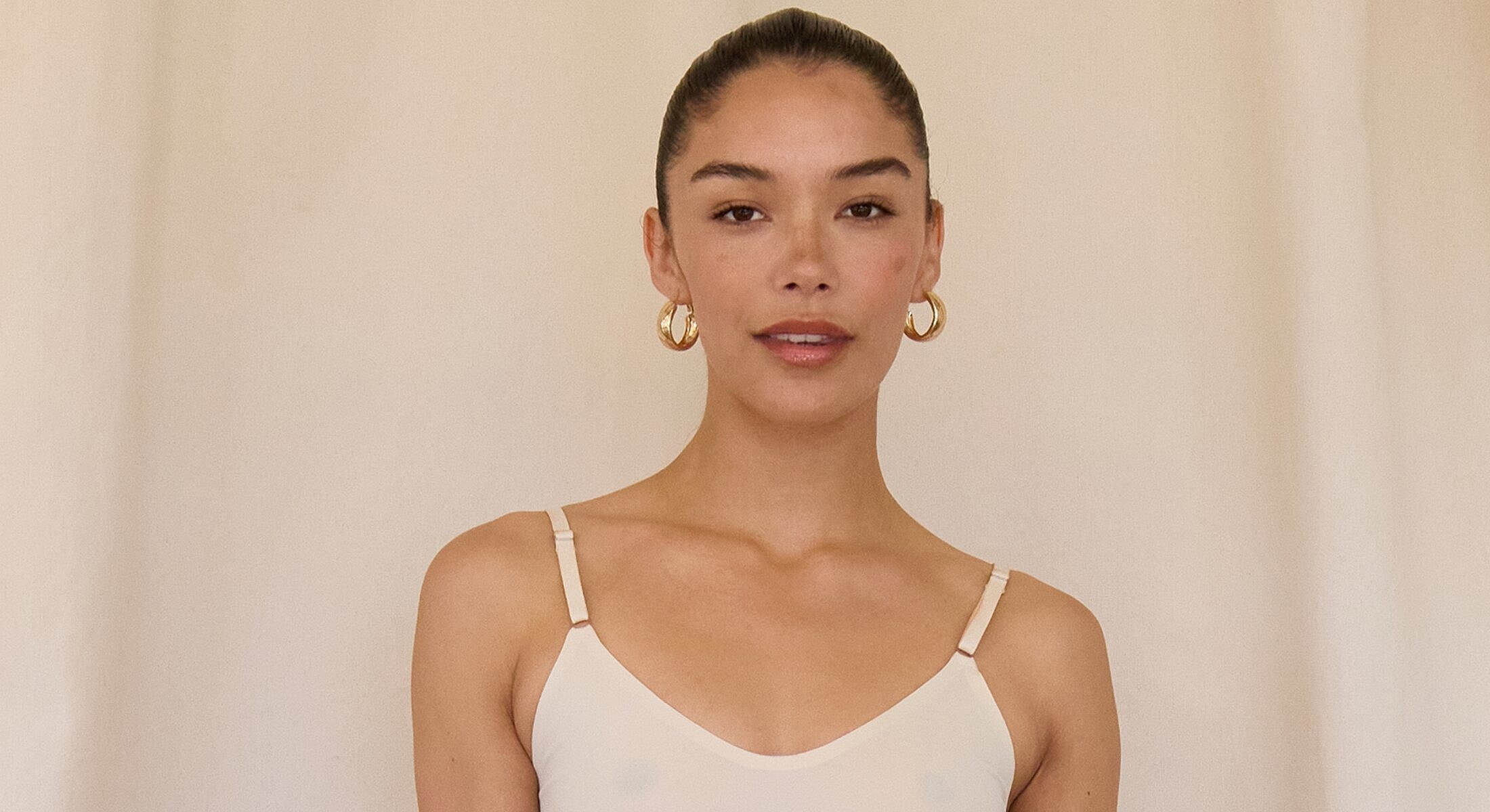 Woman in a simple tank top and earrings.